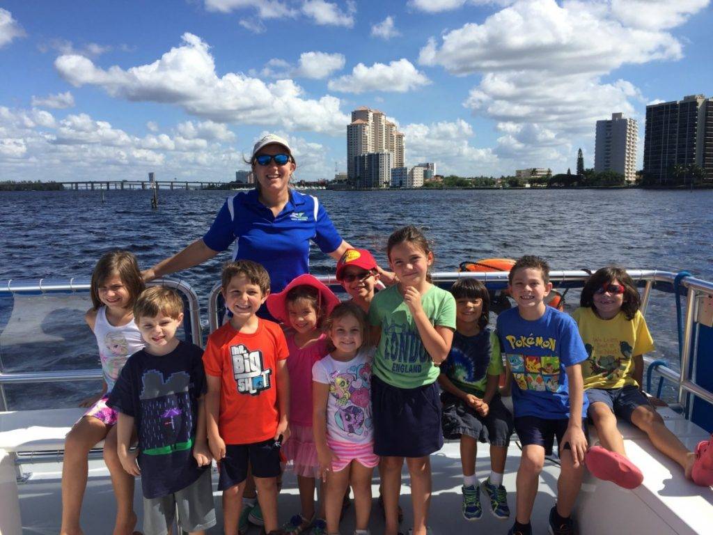 Group of ten kids and camp instructor pose on boat during marine science cruise