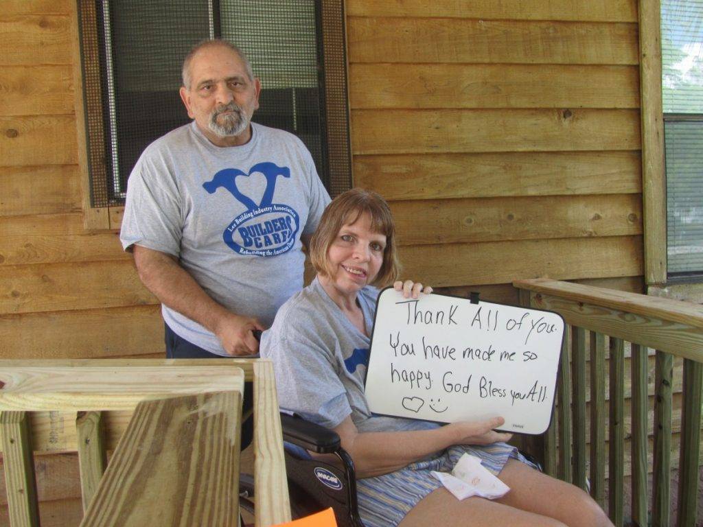 couple sits on porch with sign that reads thank all of you