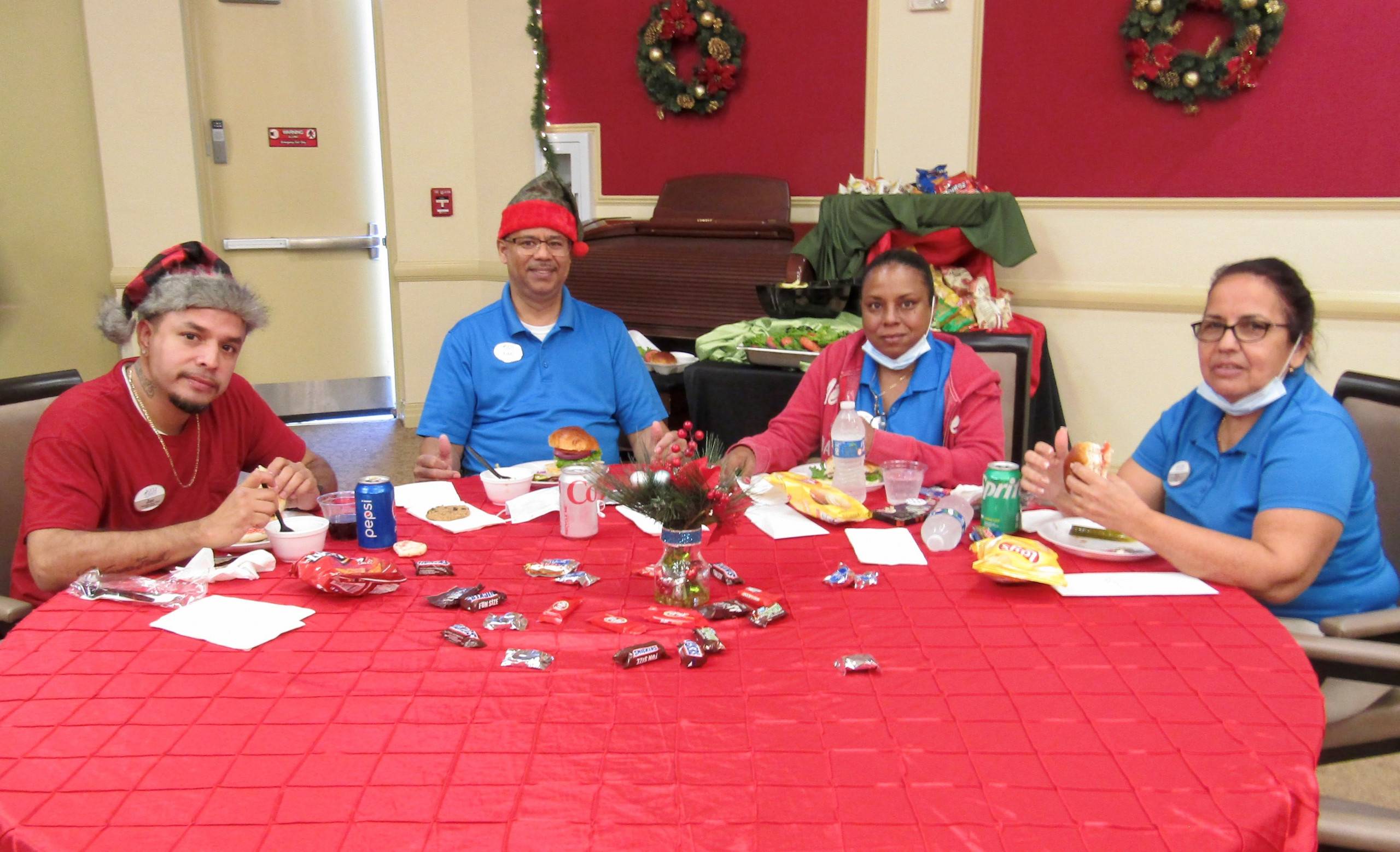 Four Gulf Coast Village staff at red holiday table