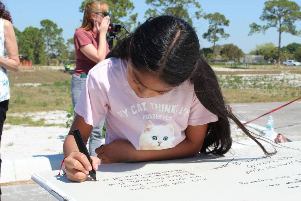 Closeup of young girl signing construction work of Immokalee Fair Housing Alliance project