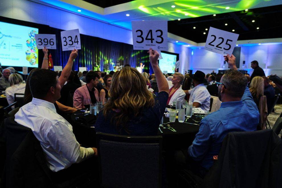 Four bidders hold up auction numbers during Autism Acceptance Awards Gala 2022
