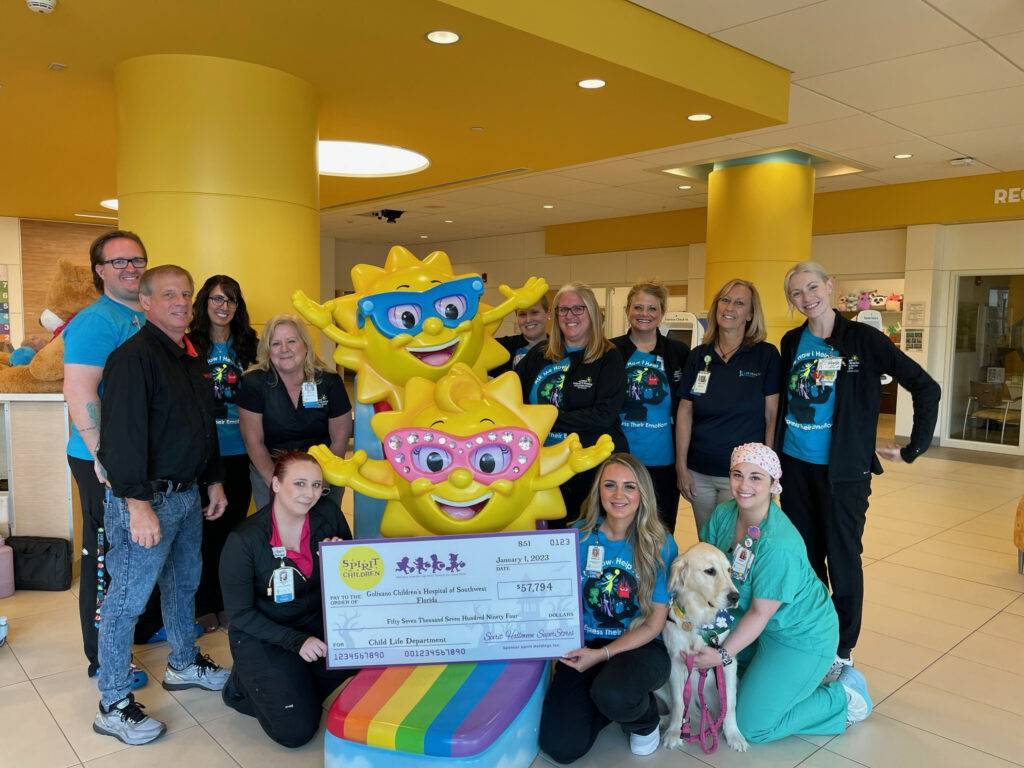 Large group photo of Lee Health staff with mascots and check donation for Golisano Children's Hospital