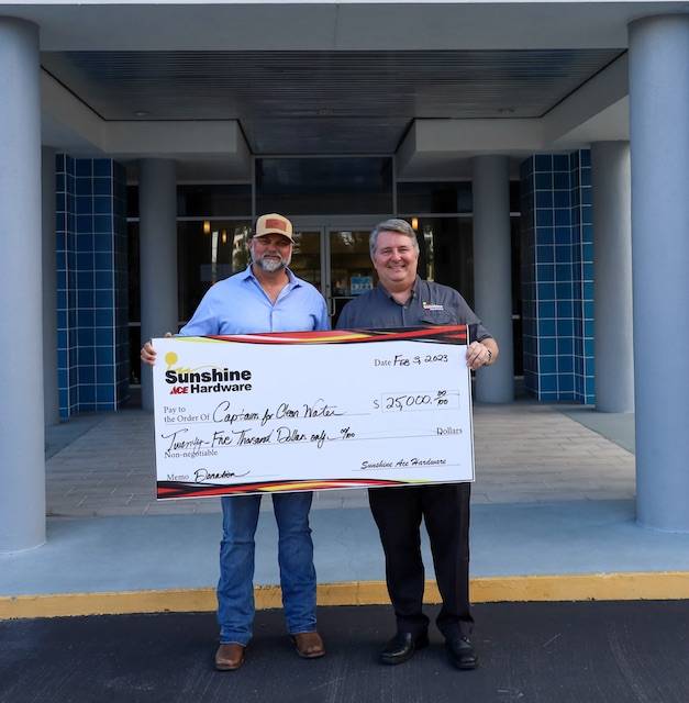 Two leadership team members hold Sunshine Ace Hardware check during $25,000 donation