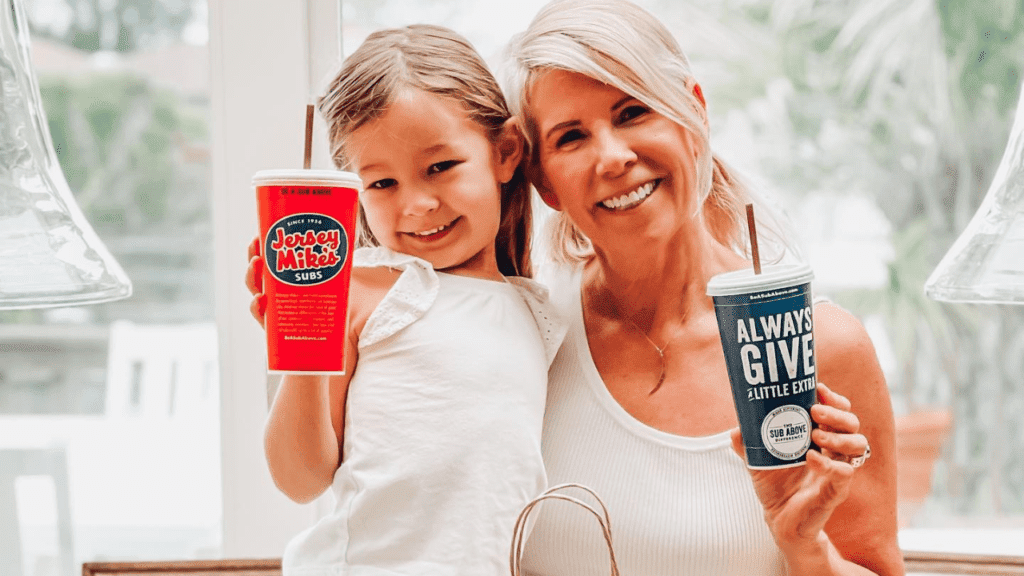 Mother and toddler daughter hold up Jersey Mike's subs cups and smile into camera