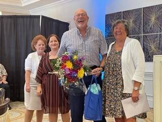 Four people laugh while holding flowers and gifts and Lee Health Regional Cancer Center