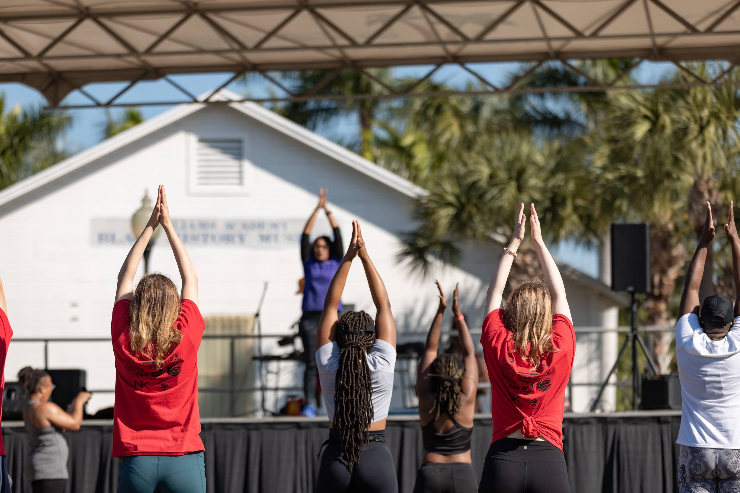 Group of women doing yoga stretching with instructor on stage at Roberto Clemente Park