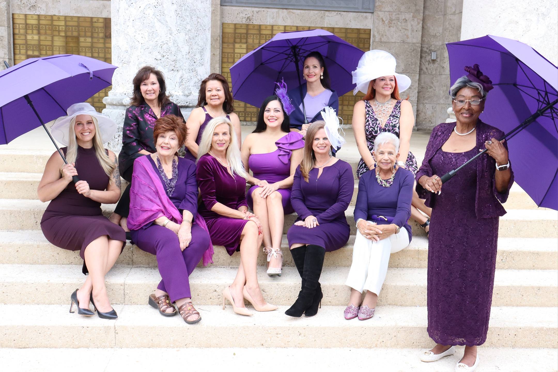 Large group of women wearing purple with umbrellas for purple tea event
